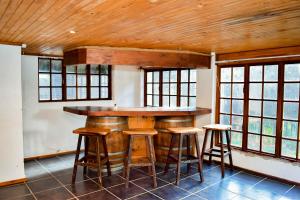 a kitchen with a bar with stools and windows at MTH in Nelspruit