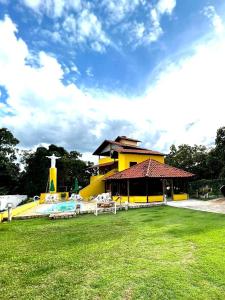 ein gelbes Gebäude mit einem Spielplatz im Gras in der Unterkunft Nova Pousada Sollaris - Coração da Serra do Cipó - MG in Santana do Riacho