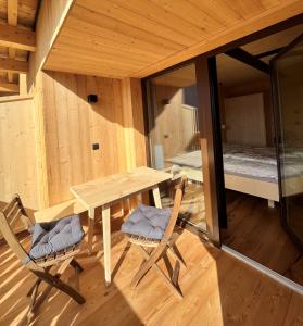 Cette chambre en bois comprend une table, des chaises et un lit. dans l'établissement Bio Felderhof, à Villa Ottone