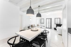 una sala da pranzo bianca con tavolo e sedie bianchi di Philosophia Luxury Villa a Megalochori