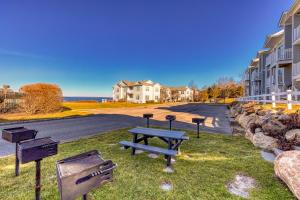 una mesa de picnic y bancos en el césped cerca de una calle en Beachside Waterview 2Br Condo w/ Pool in Greenport, en Greenport