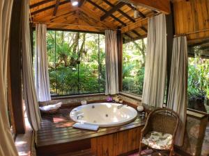 a large bath tub in a room with windows at Pousada Villa D'Amore in Monte Verde