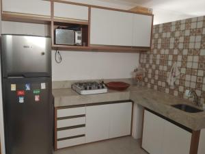 a small kitchen with a refrigerator and a sink at Apartamento Perto Praia in Salvador