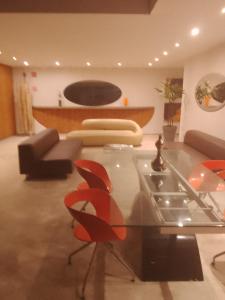 uma sala de estar com uma mesa de vidro e cadeiras vermelhas em Apartamento Perto Praia em Salvador
