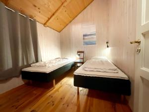 two beds in a room with wooden floors at The blacksmith's place - Cozy Rorbu in Lofoten in Sørvågen