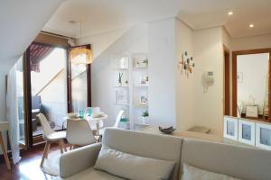 uma sala de estar com um sofá e uma mesa em Apartamento con terraza a un paso de la playa em Gijón