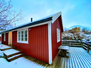 a red house with a wooden deck in the snow at The blacksmith's place - Cozy Rorbu in Lofoten in Sørvågen