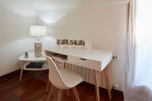 a white desk with a white chair and a lamp at Apartamento con terraza a un paso de la playa in Gijón
