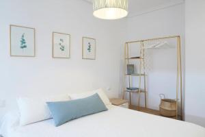 1 dormitorio con cama blanca y espejo en Apartamento con terraza a un paso de la playa en Gijón