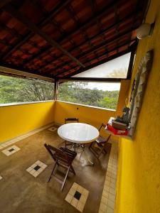 Zimmer mit einem Tisch, Stühlen und einem Fenster in der Unterkunft Nova Pousada Sollaris - Coração da Serra do Cipó - MG in Santana do Riacho