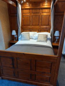 1 cama grande de madera en un dormitorio con 2 lámparas en Virginia Cottage Guest House, en Bowness-on-Windermere