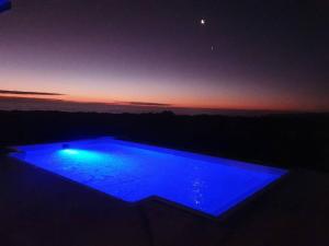 une piscine bleue avec un coucher de soleil en arrière-plan dans l'établissement Sunbird House, à Grotto Bay