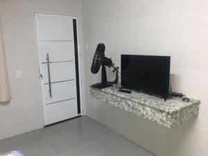 a room with a television and a phone on a wall at POUSADA COM PISCINA em PERUÍBE SABORES DA VIDA!!! in Peruíbe