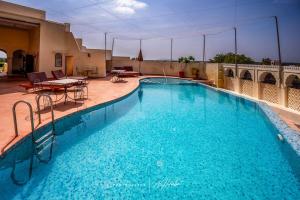 a large blue swimming pool with a table and chairs at Fort Barli - A 16th Century Castle in Barli