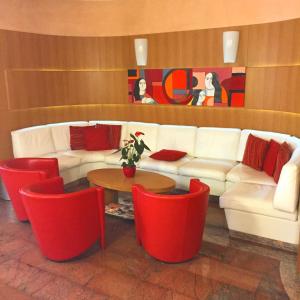 a living room with a white couch and red chairs at Le Petit Hotel in Turin