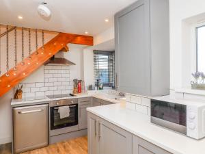a kitchen with white cabinets and a wooden staircase at Church View Cottage in Doncaster