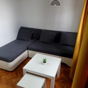 a living room with a black couch and a white table at Fenix Apartman in Zaječar