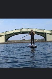 een persoon op een paddleboard in het water met een brug bij Lovely Centralised 1Bed Apt Near Town Centre & Beach - Free Wi-Fi & Parking in Fleetwood