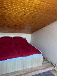 ein Bett mit roter Bettwäsche und einer Holzdecke in der Unterkunft Vivien vendégház in Zamárdi
