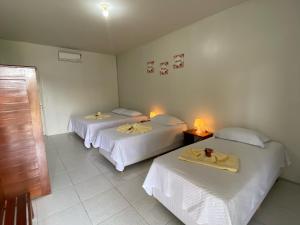two beds in a room with two tables and two lamps at POUSADA ESTRELA DA MANHÃ in Barreirinhas