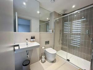 a bathroom with a toilet and a shower and a sink at Stunning Sea View Two Bed Two Bathroom Apartment in Porthcawl