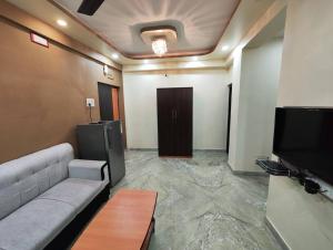 Una sala de estar con un sofá y un televisor de pantalla plana. en Stylish 2BHK Service Apartment Near Golpark, en Calcuta