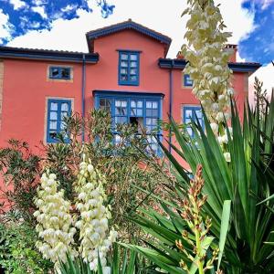 una casa roja con ventanas azules y flores blancas en La Casona Azul, espectacular palacio indiano, en Corvera