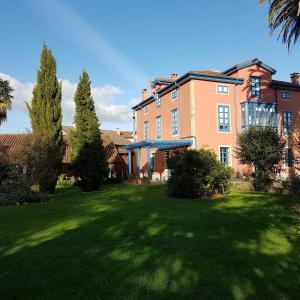 una casa grande con césped delante en La Casona Azul, espectacular palacio indiano, en Corvera