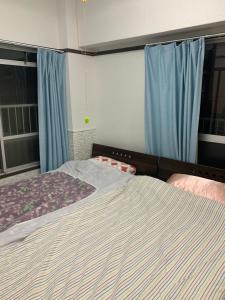 a bedroom with a large bed with blue curtains at 山下ホテル301 in Kurosakimachi