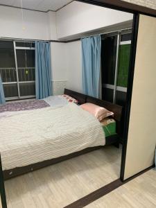 a bedroom with a bed and two windows at 山下ホテル301 in Kurosakimachi