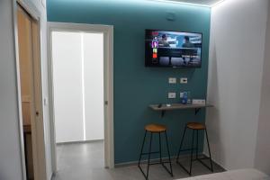 a room with two stools and a tv on the wall at The Essential - Reggia Di Caserta in Caserta +30 photos