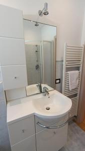 a white bathroom with a sink and a mirror at Appartamento a Madonna di Campiglio in Madonna di Campiglio