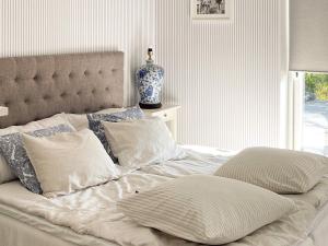埃勒斯的住宿－Holiday home ELLÖS IX，一张带枕头的白色床和一个窗户上的花瓶