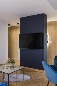 een woonkamer met een tv en een blauwe stoel en een tafel bij Modern Apart 23 in Olsztyn