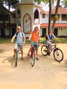 drie personen die fietsen voor een gebouw bij Vala House in Cherai Beach