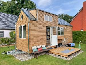 uma pequena casa com um deque num quintal em TINY HOUSE FLEESENSEE mit eigenem Garten und nur wenige Meter vom Seeufer em Göhren-Lebbin