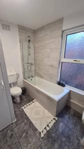 a bathroom with a tub and a toilet and a window at Entire House Near City Centre with Parking Permit (3 bedrooms, Sleeps 8) in Liverpool