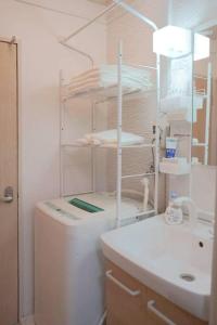 a bathroom with a sink and a toilet and a shelf at HISASHI 池下 in Nagoya