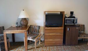 Zimmer mit einem Schreibtisch, einem TV und einem Tisch mit Stühlen. in der Unterkunft Sugar Loaf Lodge in Sedona