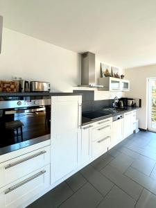 a kitchen with white cabinets and black counter tops at Ferienwohnung Magma in Lutzerath