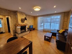 a living room with a couch and a fireplace at Mežnoras holiday house in Šņores
