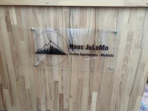 een bord aan de zijkant van een houten muur bij Haus JoLoMo in Mallnitz