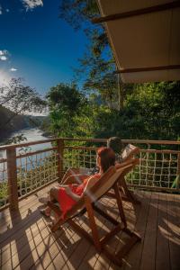 una mujer sentada en una silla en una cubierta en Pumarinri Amazon Lodge, en Tarapoto