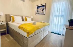 a bedroom with a large bed with a yellow blanket on it at Nature in the City lower storey Bestern in Szeged