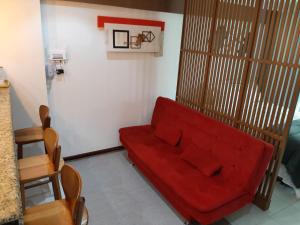 a living room with a red couch and a chair at Camboinhas LOFT Temporada in Niterói