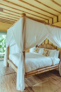 a bedroom with a canopy bed with white sheets and pillows at INARA Siargao in General Luna
