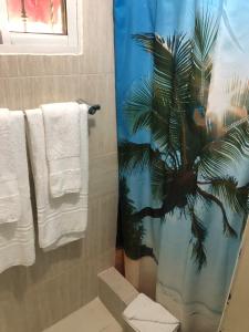 ein Badezimmer mit einem Palmenhainsvorhang und Handtüchern in der Unterkunft Hermoso Apartamento Carmen Renata III in Pantoja