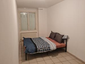 małe łóżko w pokoju z oknem w obiekcie Fabuleux t3 refait à neuf avec cour intérieure w mieście Saint-Étienne