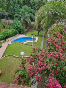 een tuin met een zwembad en roze bloemen bij Casa Al pie del Cerro in Yerba Buena