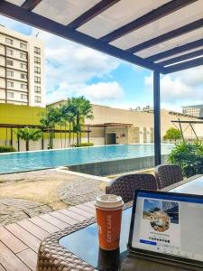 un ordenador portátil en una mesa junto a la piscina en Hidden Gem of Centrio Tower CDO, en Cagayan de Oro